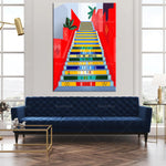 L'image montre un escalier coloré et fantaisiste avec l'inscription "Rio de Janeiro" en haut, entouré de végétation luxuriante, placé dans un beau salon avec de grandes fenêtres et un canapé bleu foncé.