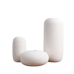 Trois vases blancs de tailles variées, avec des motifs de lignes horizontales dans un style minimaliste et épuré.
