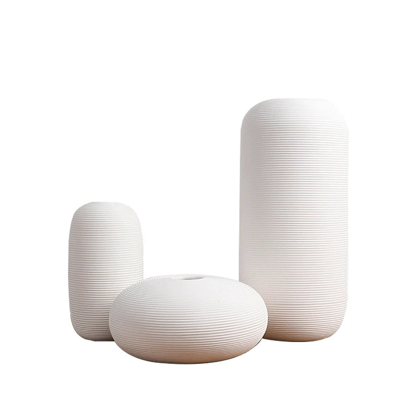 Trois vases blancs de tailles variées, avec des motifs de lignes horizontales dans un style minimaliste et épuré.