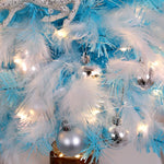 Sapin de Noël plume rose placé sur une étagère avec d'autres décorations festives