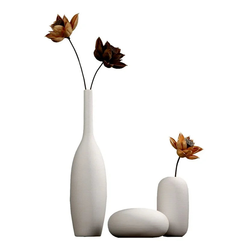 Trois vases blancs minimalistes contenant de belles fleurs d'automne à pétales orange et bruns.