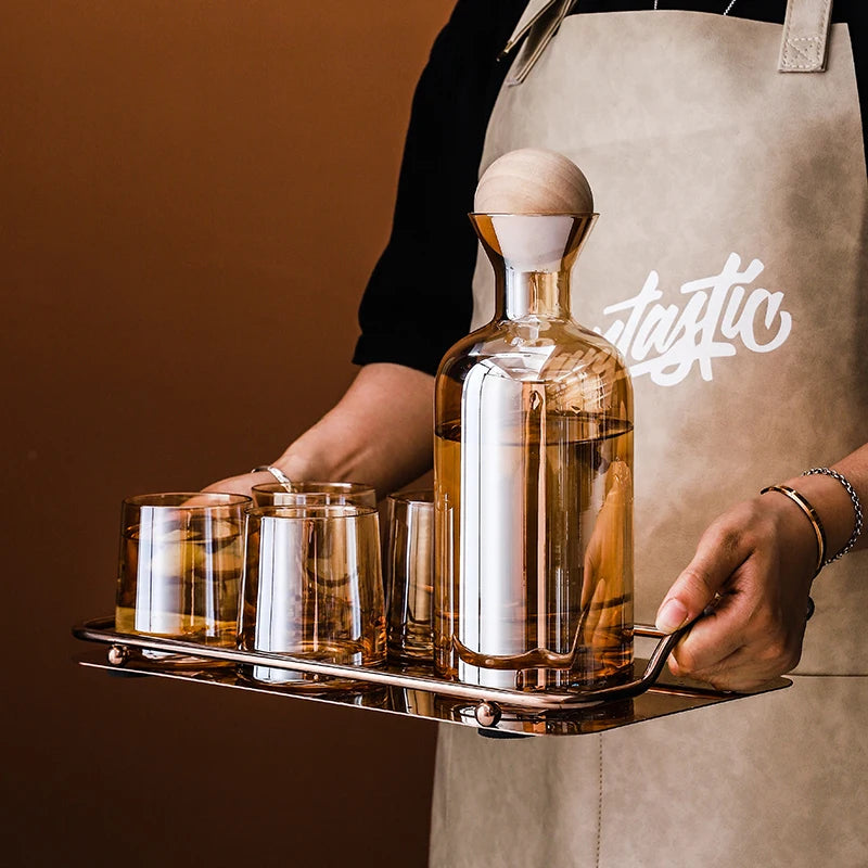 Une bouteille de liqueur en verre fine et élégante posée sur un plateau en métal, accompagnée de verres à shot, créant une présentation attrayante et sophistiquée du produit.