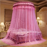 Magnifique ciel de lit rose décoratif avec du tulle et des ornements élégants, installé sur un lit douillet et luxueux dans une chambre meublée avec goût.