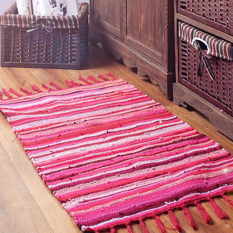 Un tapis en coton multicolore avec des rayures rose vif sur le sol en bois, complété par des paniers en osier.