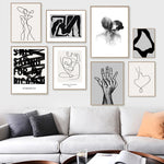 Un mur décoré d'un ensemble d'œuvres d'art abstraites en noir et blanc, comprenant des silhouettes humaines, des formes géométriques et des éléments graphiques, créant une ambiance artistique et épurée dans ce salon.