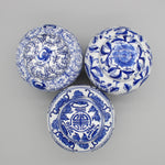 Trois magnifiques boules décoratives en porcelaine blanche et bleue, avec des motifs floraux et des éléments géométriques typiques de l'art céramique asiatique.