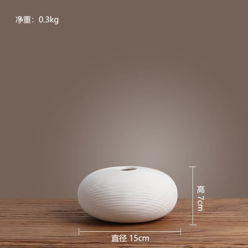 Vase blanc en céramique avec motif de lignes ondulées, posé sur une surface en bois, mesurant 15 cm de diamètre et 7 cm de hauteur, avec un poids de 0,3 kg.