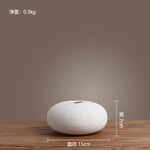 Vase blanc en céramique avec motif de lignes ondulées, posé sur une surface en bois, mesurant 15 cm de diamètre et 7 cm de hauteur, avec un poids de 0,3 kg.