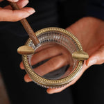 Ce miroir vintage orné de motifs dorés et d'un contour dentelé semble être un accessoire de beauté élégant et raffiné.