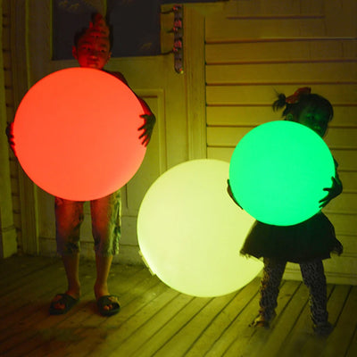 Boule lumineuse LED étanche rouge allumée dans un jardin de nuit