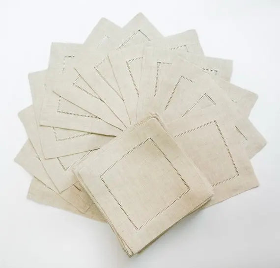 Une pile de serviettes de table beige avec des coutures décoratives autour des bords.