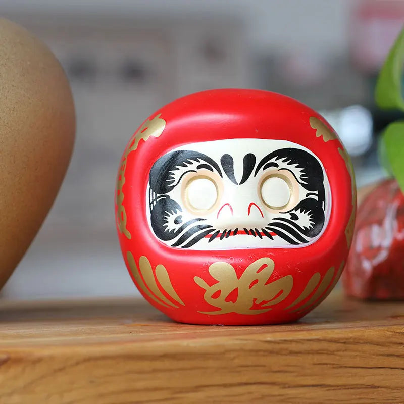 statuette japonaise daruma rouge blanche visage sourire motifs dorés traditionnels feng shui ornement chance