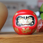 statuette japonaise daruma rouge blanche visage sourire motifs dorés traditionnels feng shui ornement chance