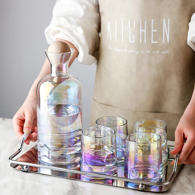 Une élégante carafe en verre avec des verres à cocktail multicolores, le tout posé sur un plateau argenté, complète ce mobilier de cuisine accueillant.