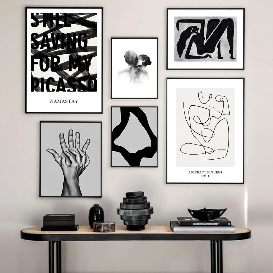 Cette galerie murale affiche une variété d'œuvres d'art abstraites en noir et blanc, comprenant des affiches typographiques, des silhouettes de corps, des images de mains et des compositions géométriques, créant une présentation esthétique et harmonieuse.