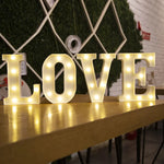 Lettre lumineuse LED blanche sur table de chevet dans une chambre