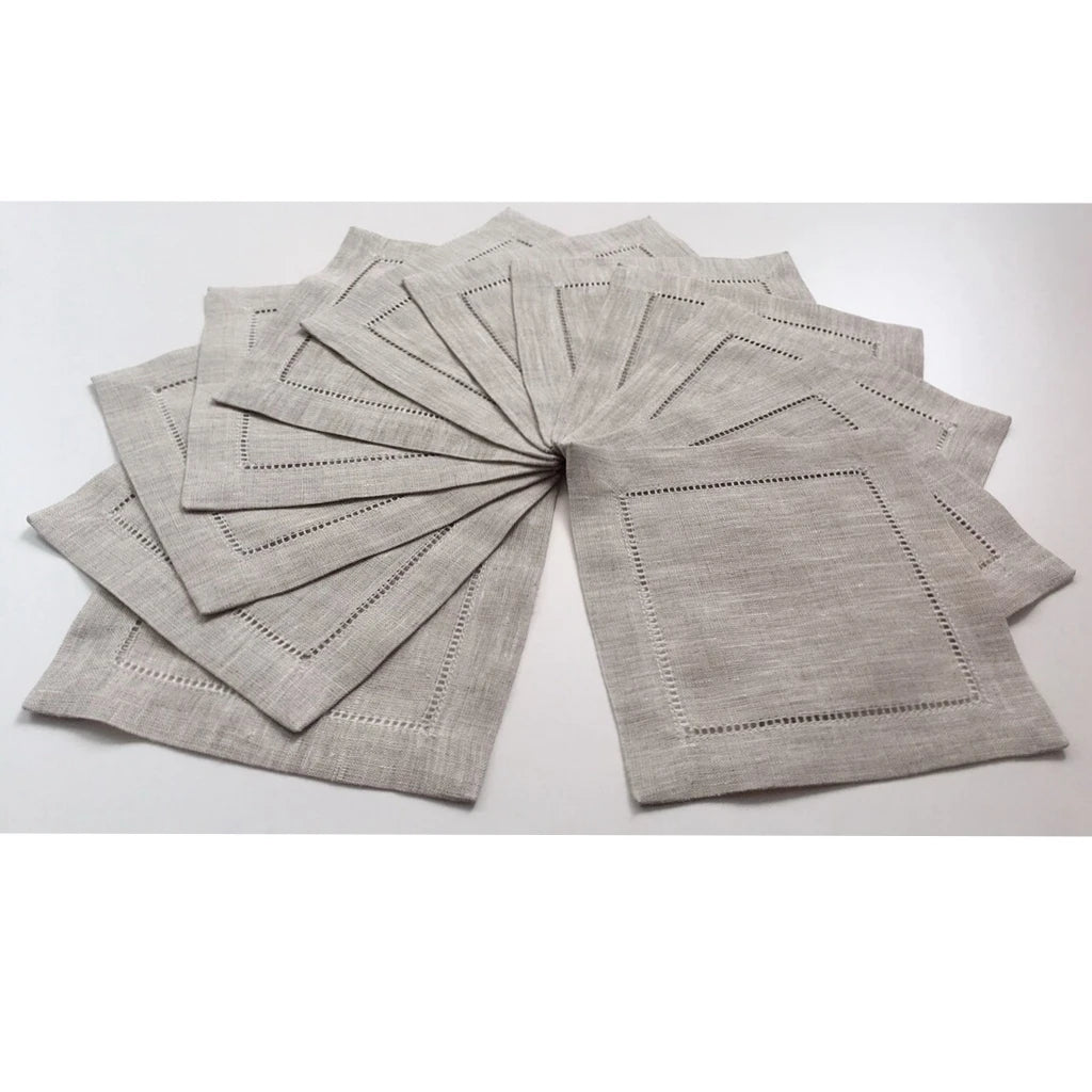 Une pile de serviettes de table en lin gris, avec des motifs de couture délicats et un style minimaliste.