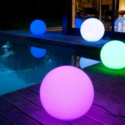 Boule lumineuse LED étanche rouge dans un jardin de nuit