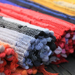 Des pelotes de fils colorés, rouges, bleus et gris, entrelacées, formant un motif texturé et décoratif.