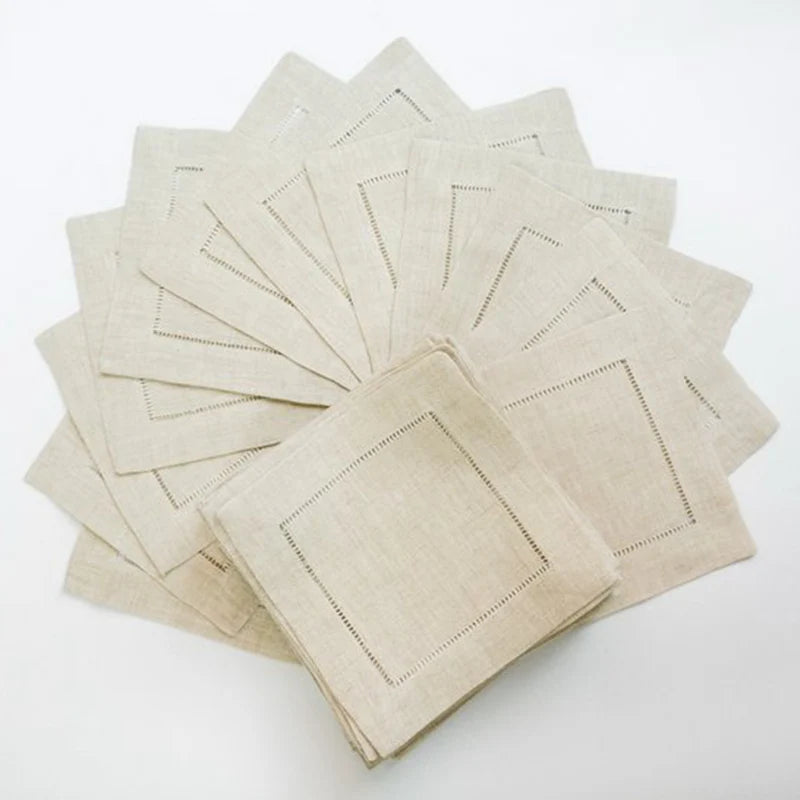 Pile de serviettes de table en lin beige pliées avec des bordures décoratives brodées.