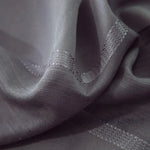 Gros plan sur la texture du tissu du voilage gris foncé, révélant les fibres tissées et les bandes légèrement brillantes.