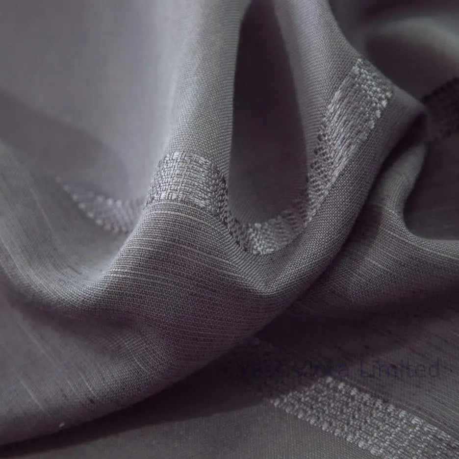 Gros plan sur la texture du tissu du voilage gris foncé, révélant les fibres tissées et les bandes légèrement brillantes.