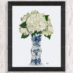 Un vase en céramique bleue et blanche rempli d'une belle composition de fleurs d'hortensia blanches.