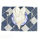 Cadre de table géométrique bleu marine et blanc avec assiette, couverts et tissu décoratif.