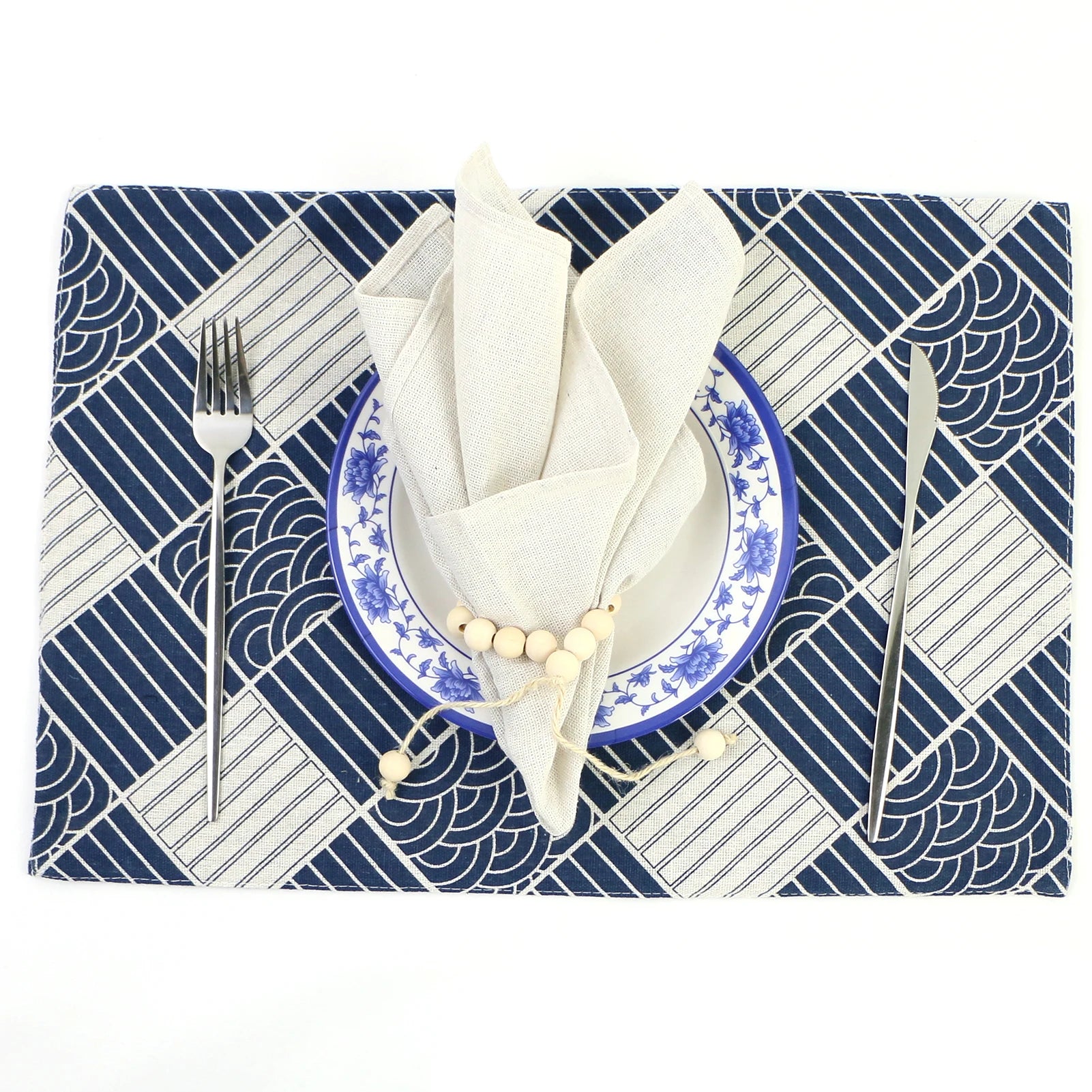 Cadre de table géométrique bleu marine et blanc avec assiette, couverts et tissu décoratif.