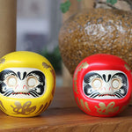 statuette japonaise daruma rouge blanche visage sourire motifs dorés traditionnels feng shui ornement chance