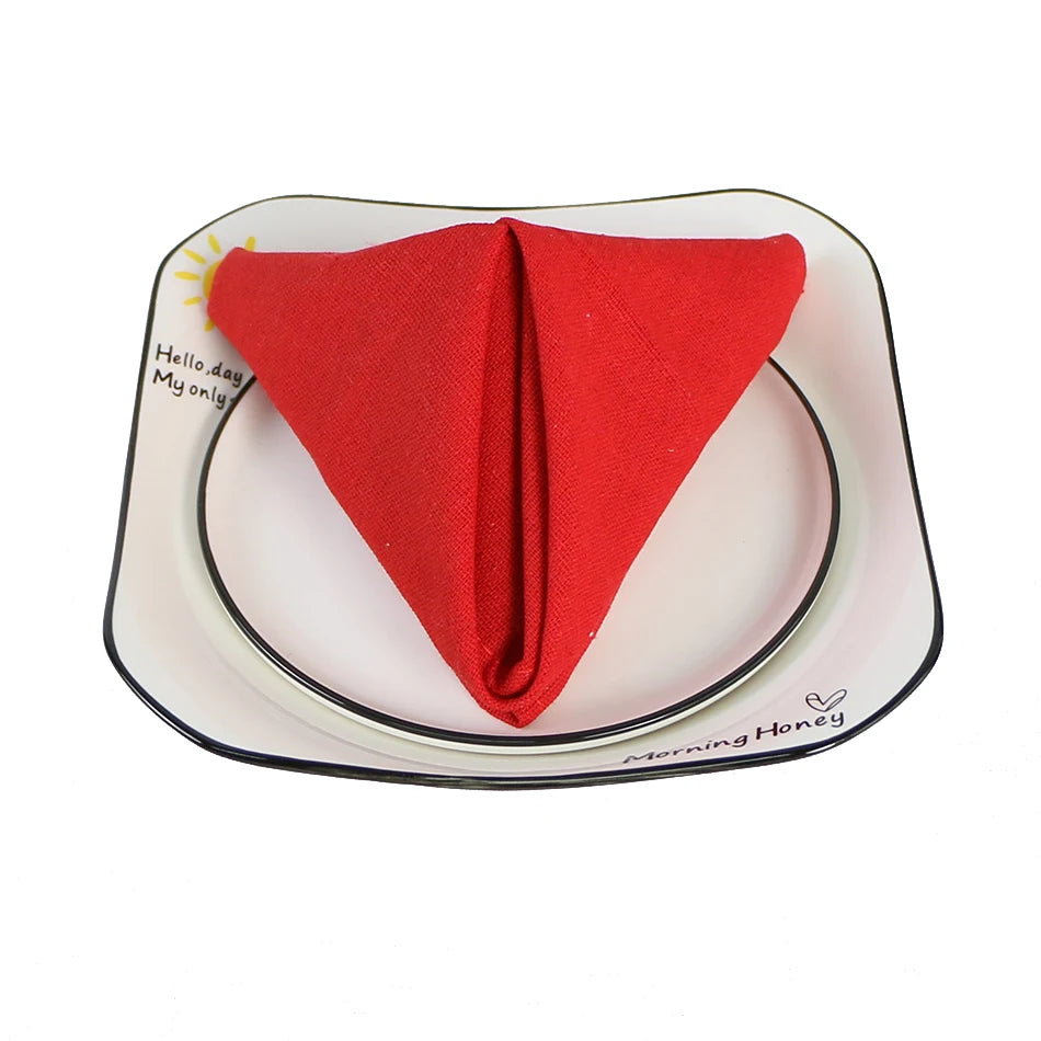 Une serviette en tissu rouge vif, présentée sur une assiette décorative blanche et noire, avec l'inscription "Hello day, my only Morning Honey" au centre.