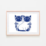 Deux chats bleus stylisés dans un cadre de bois sur un fond blanc.