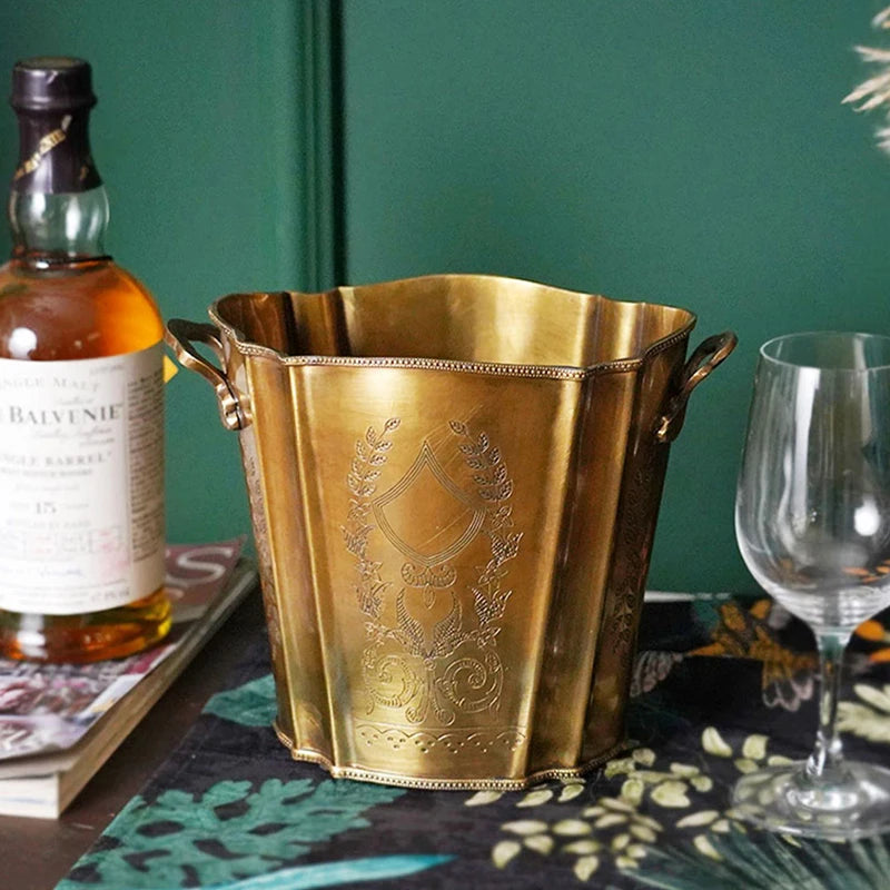 Une belle vasque dorée ornée de motifs élégants, entourant une bouteille de liqueur et des verres sur une table élégamment décorée.