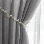 Rideau élégant en couleur grise avec embrasse décorative de perles et cristaux, parfait pour ajouter une touche raffinée à la décoration intérieure. Accessoire idéal pour personnaliser un salon ou une chambre, ce rideau apporte une ambiance chic et moderne. Adapté pour filtrer la lumière et créer une atmosphère apaisante.