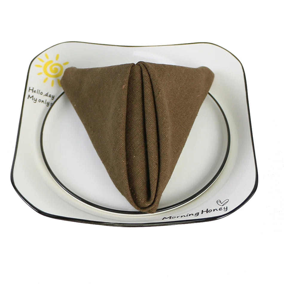 Assiette ronde blanche avec un gros pli de linge brun placé au centre.