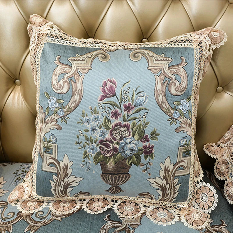 Coussin vintage avec motif floral élégant dans un design rétro sur un fond bleu vert, avec une bordure en dentelle blanche.