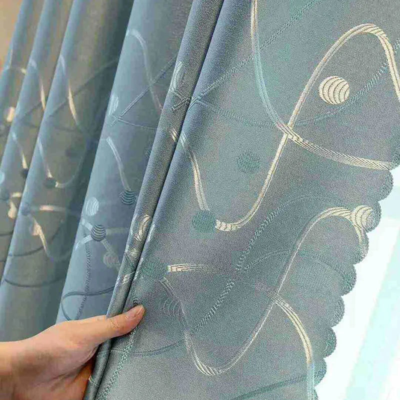 Vue rapprochée d’un rideau bleu à motifs jacquard abstraits, tenu à la main pour en dévoiler la texture et la finesse du tissage.