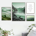 Cette image présente un paysage de montagne avec un lac calme et des rochers au premier plan, entouré de brume et de végétation verdoyante. Un cadre inspirant et apaisant.