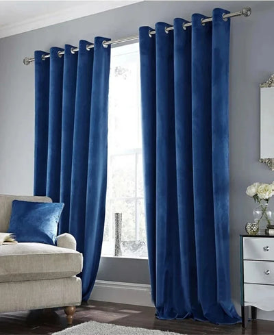 Rideau en velours bleu roi à œillets, installé dans un salon moderne avec canapé beige et mur gris clair, apportant une touche chic et chaleureuse à la pièce.