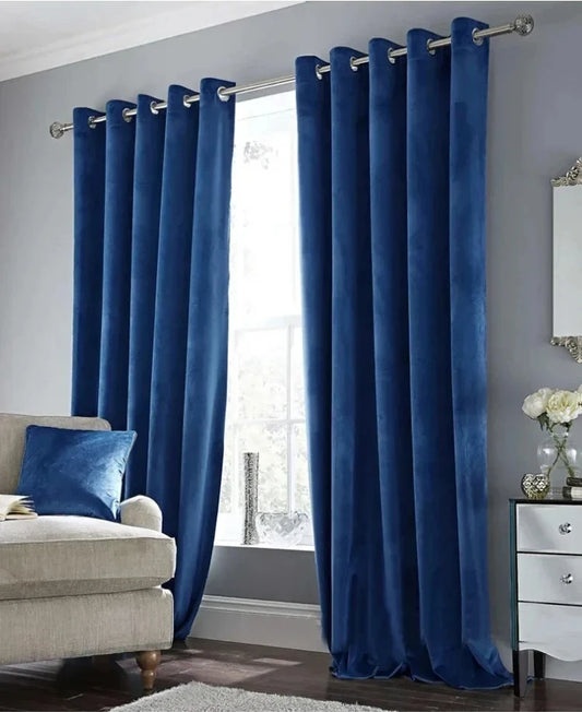Rideau en velours bleu roi à œillets, installé dans un salon moderne avec canapé beige et mur gris clair, apportant une touche chic et chaleureuse à la pièce.