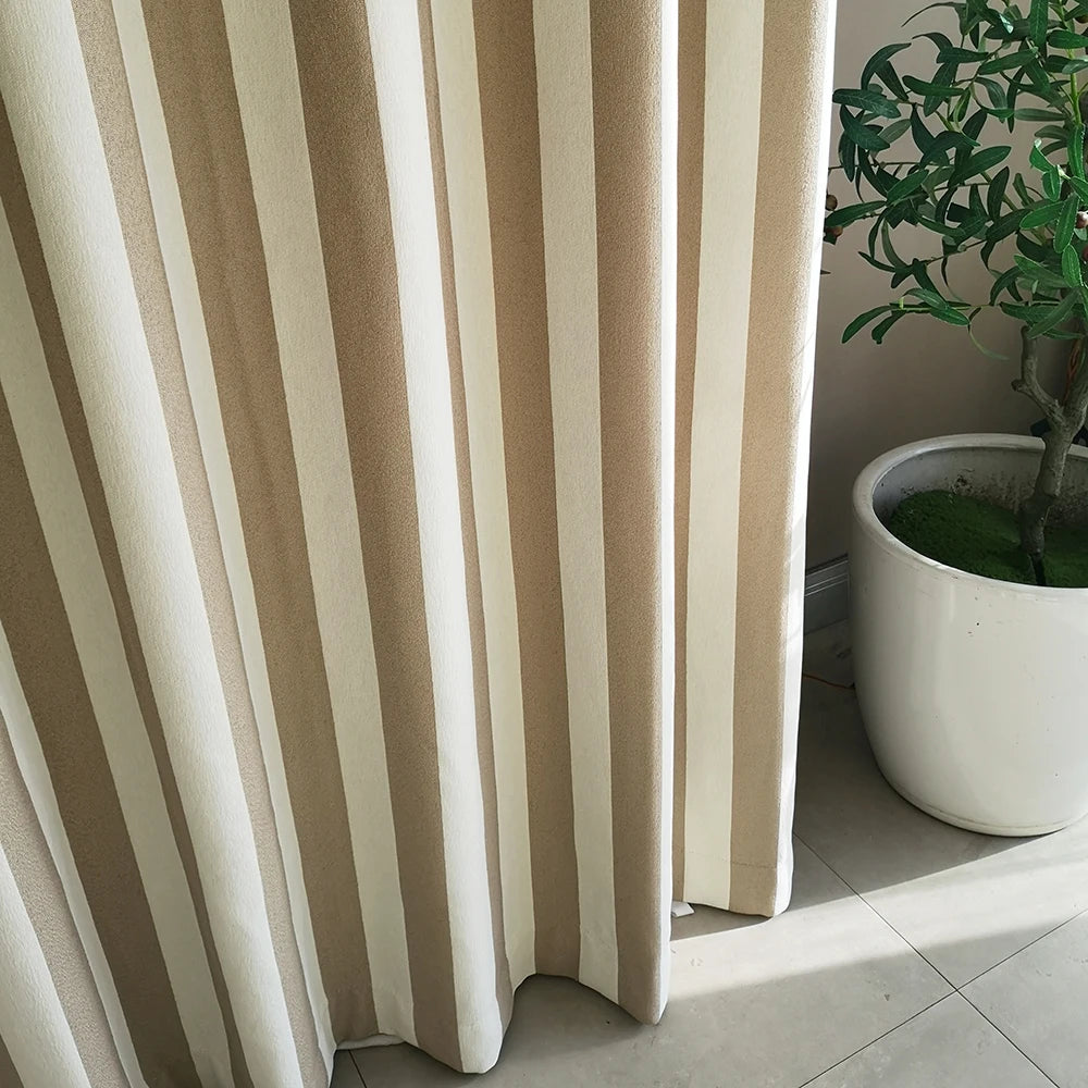 Voilage tamisant à rayures verticales beige et blanc, installé devant une fenêtre avec un pot de plante verte en céramique blanche