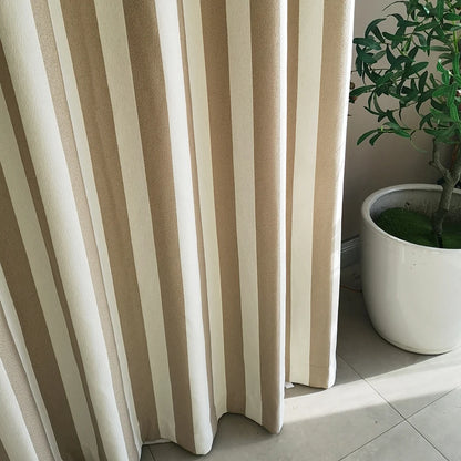 Voilage tamisant à rayures verticales beige et blanc, installé devant une fenêtre avec un pot de plante verte en céramique blanche