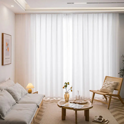 Vue d’ensemble d’un salon chaleureux avec de longs voilages blancs installés au plafond sur rail, offrant un éclairage naturel.