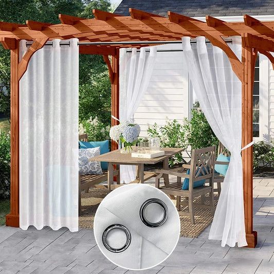Voilages imperméables blancs accrochés à une pergola en bois, créant un coin repas extérieur élégant et protégé.