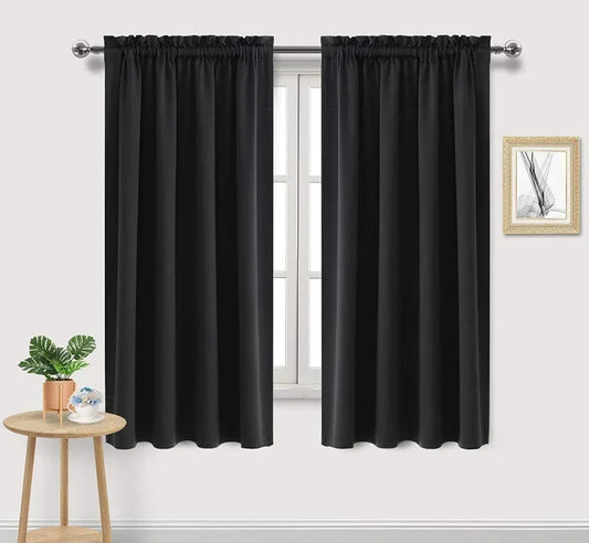 Deux panneaux de rideaux occultants noirs installés sur une tringle avec finition froncée, ambiance épurée dans un intérieur lumineux.