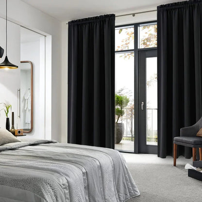 Rideaux occultants noirs installés dans une chambre contemporaine avec baie vitrée, créant une ambiance cosy et reposante.
