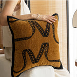 Coussin décoratif en tissu texturé jaune et noir avec des motifs géométriques.