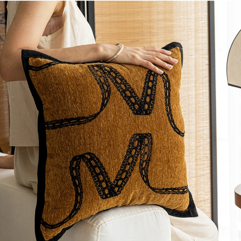 Coussin décoratif en tissu texturé jaune et noir avec des motifs géométriques.