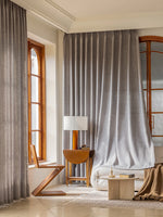 Voilage occultant gris clair habillant de grandes fenêtres dans un salon lumineux.