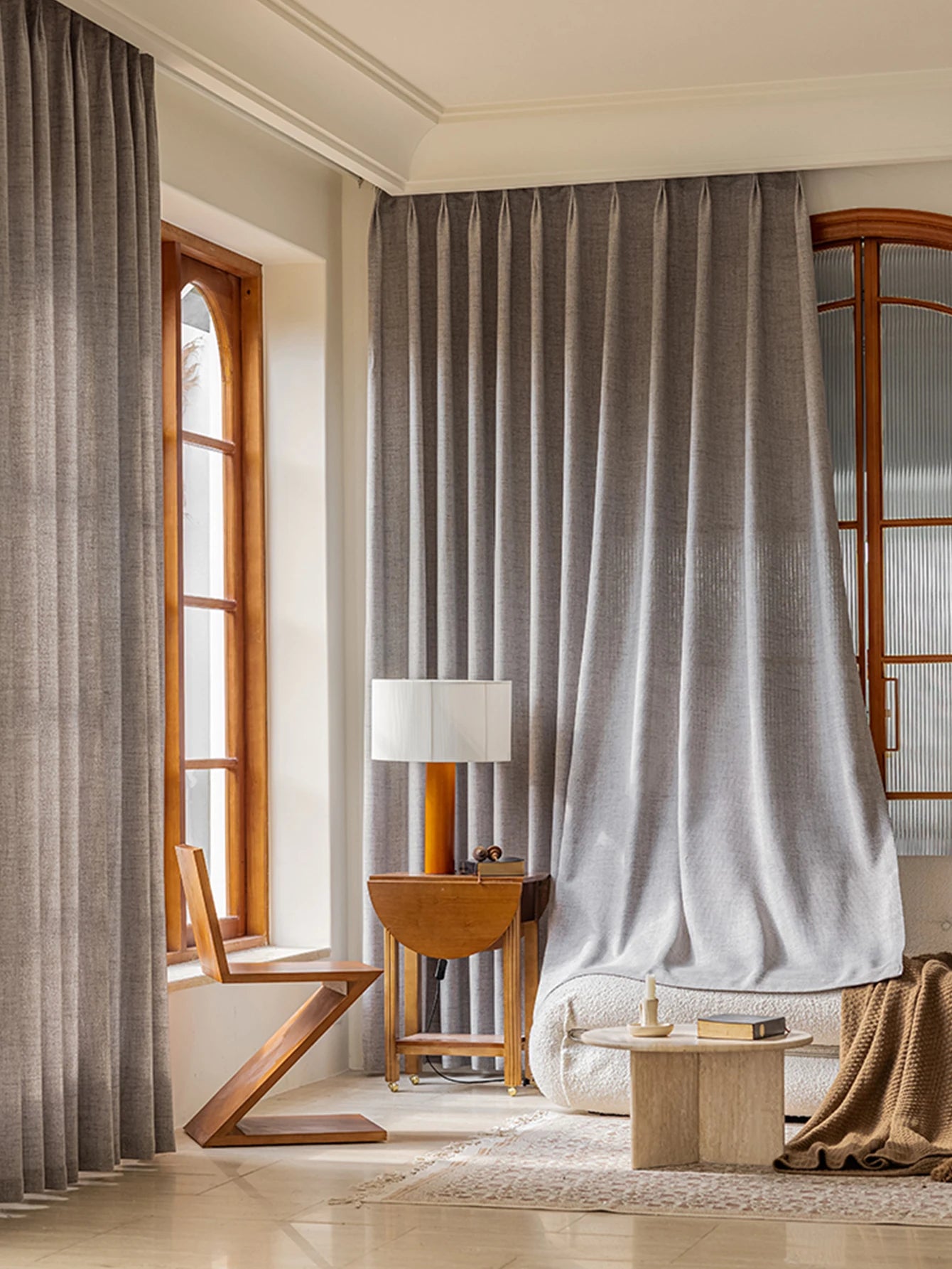 Voilage occultant gris clair habillant de grandes fenêtres dans un salon lumineux.